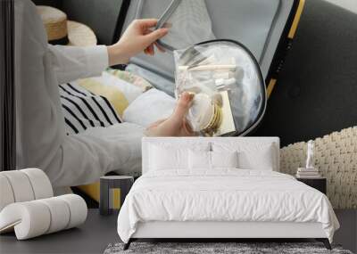 Woman packing suitcase for trip on sofa, closeup Wall mural