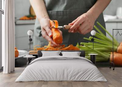 Woman peeling fresh carrot at dark gray table in kitchen, closeup Wall mural