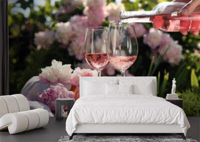 Woman pouring rose wine into glass at table in garden, closeup Wall mural