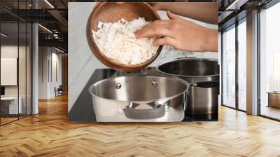 Woman pouring wax flakes into pot on scale in kitchen, closeup. Making homemade candles Wall mural