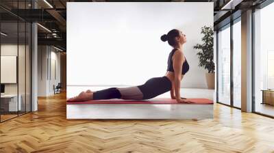 Woman practicing cobra asana in yoga studio. Bhujangasana pose Wall mural