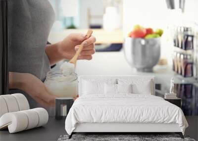 Woman putting coconut oil on frying pan in kitchen, closeup Wall mural