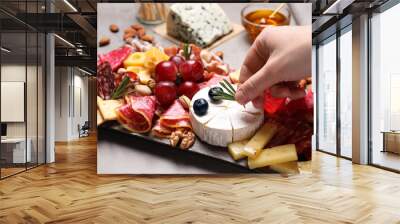 Woman putting rosemary on board with different appetizers, closeup Wall mural