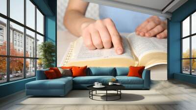 Woman reading Bible at white wooden table, closeup Wall mural