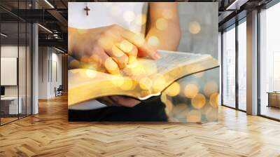 Woman reading Bible near white wall, closeup. Bokeh effect Wall mural