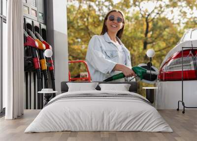 Woman refueling car at self service gas station Wall mural