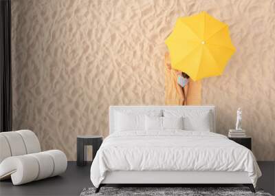 Woman resting under yellow beach umbrella at sandy coast, aerial view. Space for text Wall mural