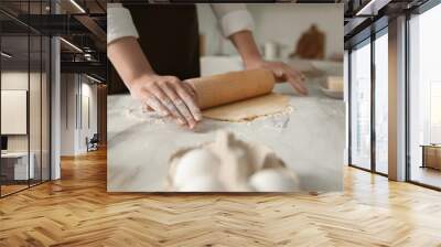 Woman rolling dough at table in kitchen, closeup Wall mural