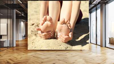 Woman sitting barefoot on sand outdoors, closeup Wall mural