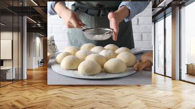 Woman sprinkling flour over dough balls at grey table, closeup Wall mural