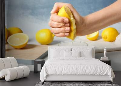 Woman squeezing lemon juice into glass on table Wall mural