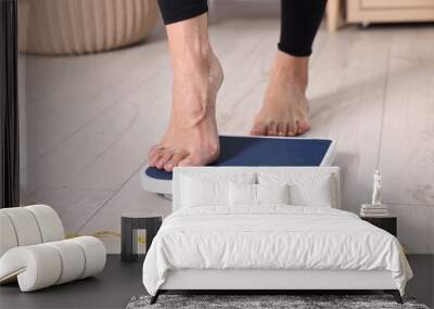 Woman stepping on floor scale and measuring tape at home, closeup. Weight control Wall mural