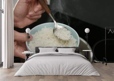 Woman taking boiled rice from pot into bowl, closeup Wall mural