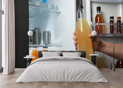 Woman taking bottle with drink from refrigerator, closeup Wall mural