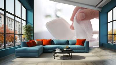 Woman taking wet wipe from pack on blurred background, closeup Wall mural