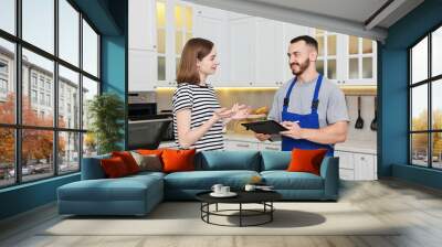 Woman talking with smiling repairman near oven in kitchen Wall mural