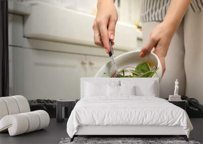 Woman throwing vegetable salad into bin indoors, closeup Wall mural