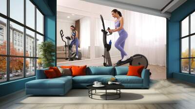 Woman using modern elliptical machine at home Wall mural