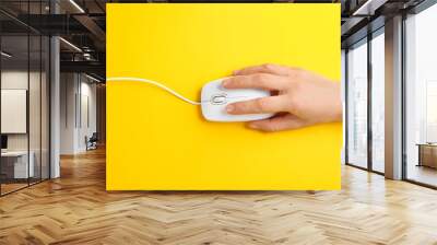 Woman using modern wired optical mouse on yellow background, top view Wall mural