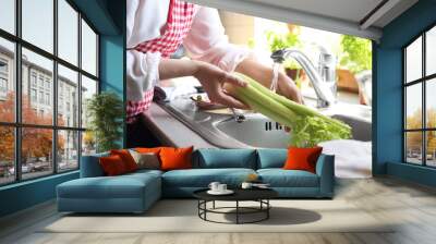 Woman washing fresh celery in kitchen sink, closeup Wall mural