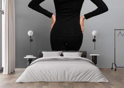 Woman wearing thermal underwear on grey background, back view Wall mural