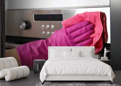 Woman wiping electric oven with rag in kitchen, closeup Wall mural