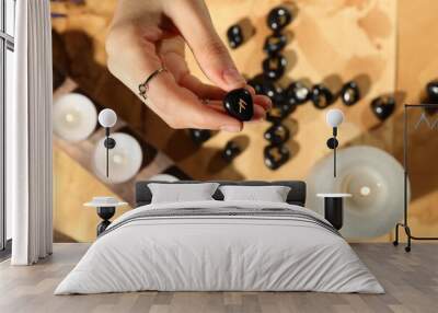 Woman with black runes at table, top view Wall mural