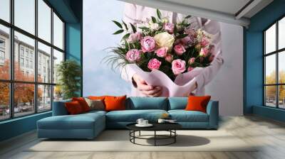 Woman with bouquet of beautiful roses on light blue background, closeup Wall mural