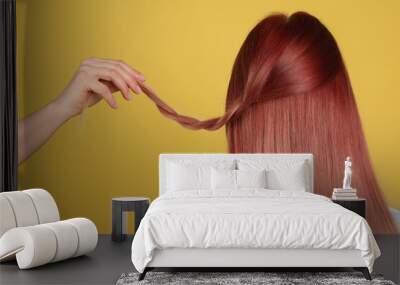 Woman with bright dyed hair on yellow background, back view Wall mural