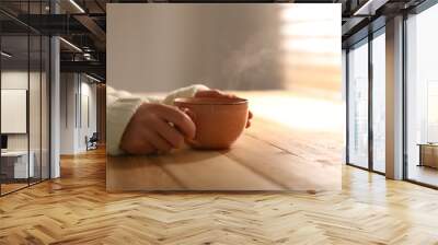 Woman with cup of tasty coffee at wooden table, closeup. Good morning Wall mural