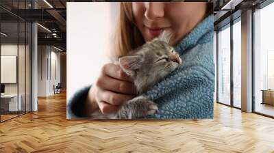 Woman with cute fluffy kitten against light background, closeup Wall mural