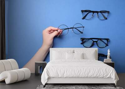 Woman with different stylish glasses on blue background, top view Wall mural