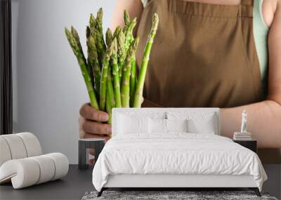 Woman with fresh asparagus stems on light grey background, closeup Wall mural