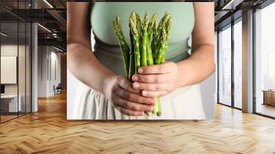 Woman with fresh asparagus stems on light grey background, closeup Wall mural