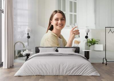 Woman with glass of tap water in kitchen Wall mural