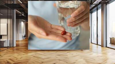 Woman with glass of water and pill indoors, closeup Wall mural