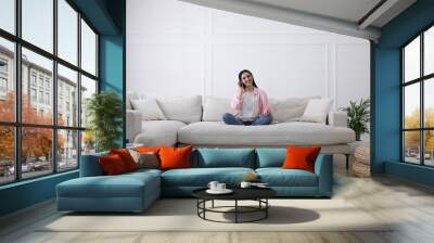 Woman with headphones on sofa in living room Wall mural