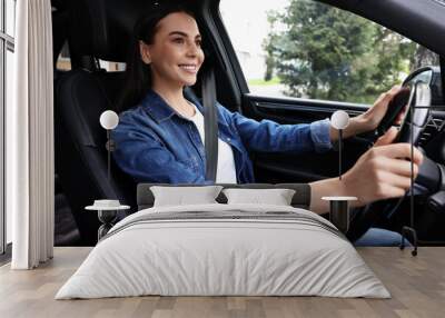 Woman with seatbelt holding steering wheel while driving her car Wall mural