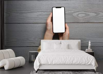 Woman with smartphone at grey wooden table, top view Wall mural