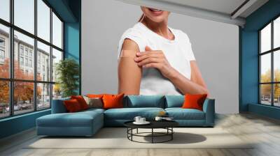 Woman with sticking plaster on arm after vaccination against light grey background, closeup Wall mural