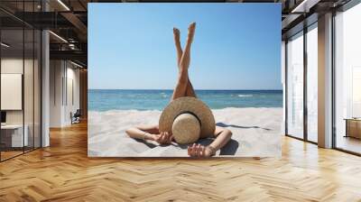 Woman with straw hat lying on sandy beach near sea Wall mural