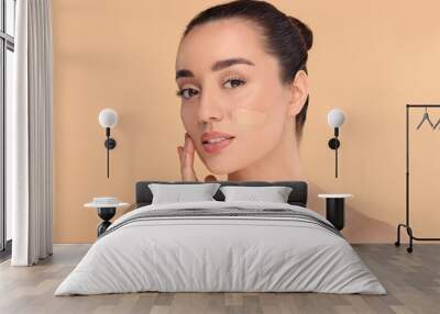 Woman with swatch of foundation on face against beige background Wall mural