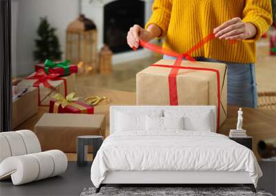 Woman wrapping Christmas gift at wooden table indoors, closeup Wall mural