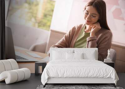 Woman writing letter at wooden table in room Wall mural