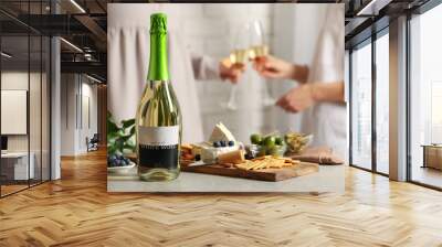 Women clinking glasses indoors, focus on table with bottle of wine and different snacks. Space for text Wall mural