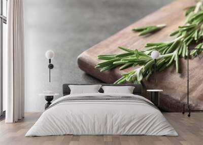 Wooden board with fresh rosemary twigs on table, closeup Wall mural