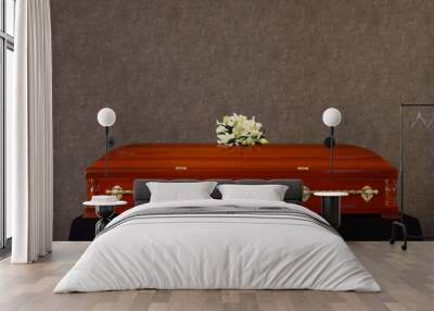 Wooden funeral casket with white lilies at grey wall Wall mural