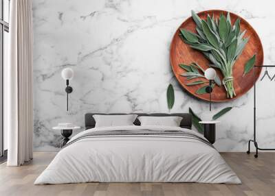 Wooden plate with fresh green sage on white marble  table, flat lay. Space for text Wall mural