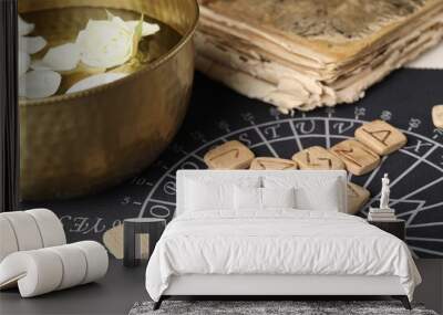 Wooden runes, old book and bowl with flower petals in water on divination mat, closeup Wall mural