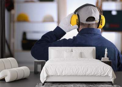 Worker wearing safety headphones indoors, back view. Hearing protection device Wall mural